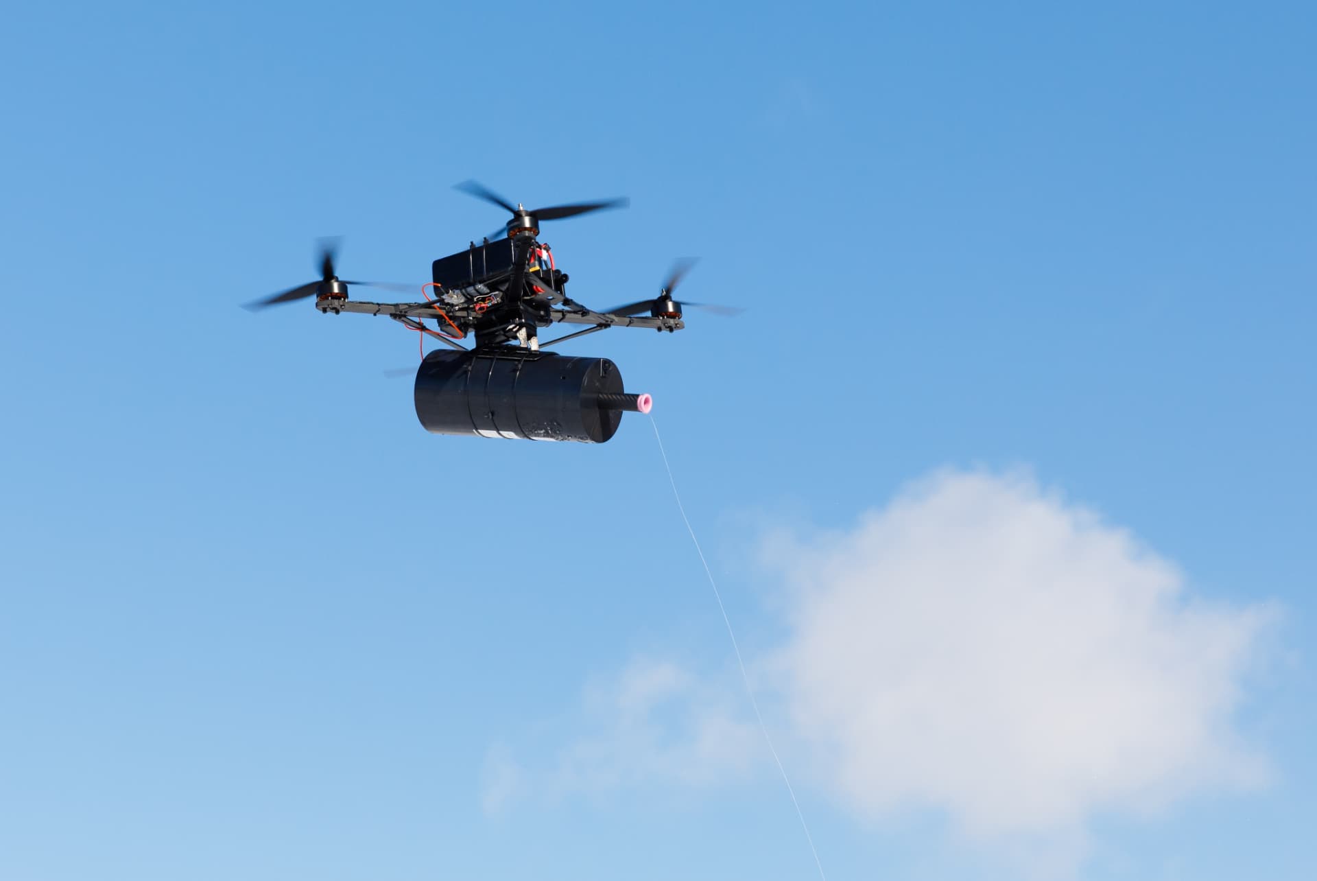 Fibre-optic-controlled quad-rotor drone with spool trailing a filament